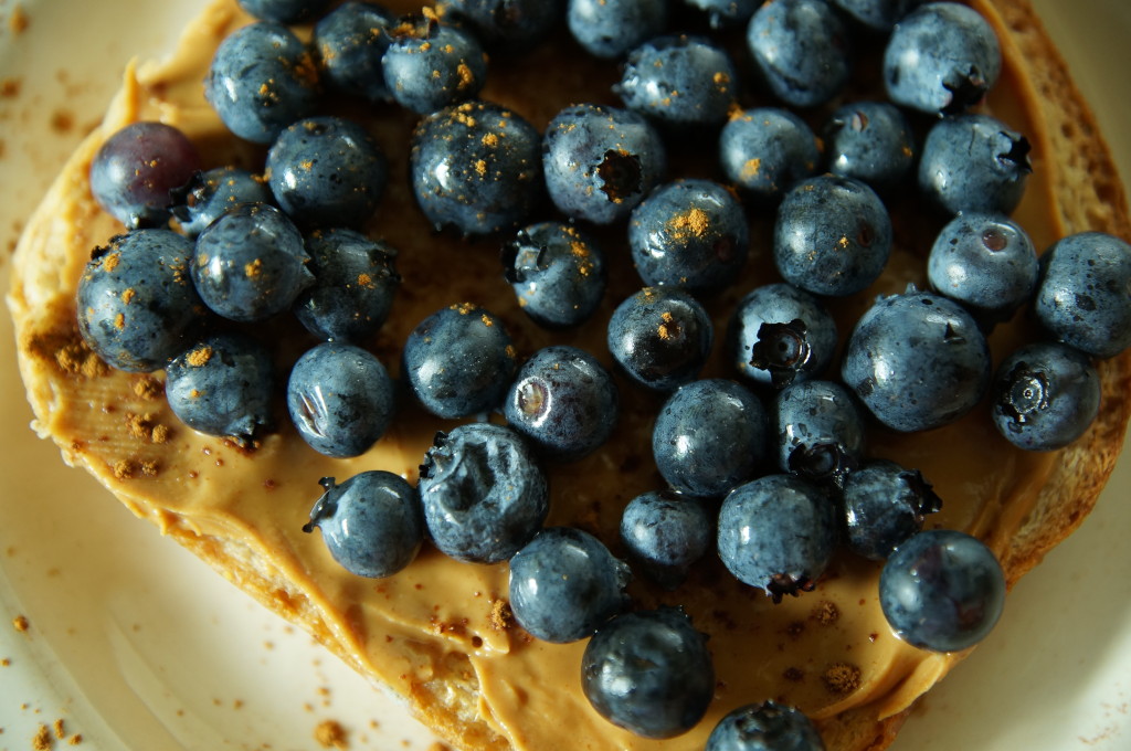 whole wheat bread spread with peanut butter and topped with fruit (blueberries)
